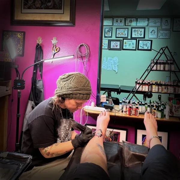 Brittany tattooing a client's foot in the Alien Phone Tattoo studio in Fort Walton Beach